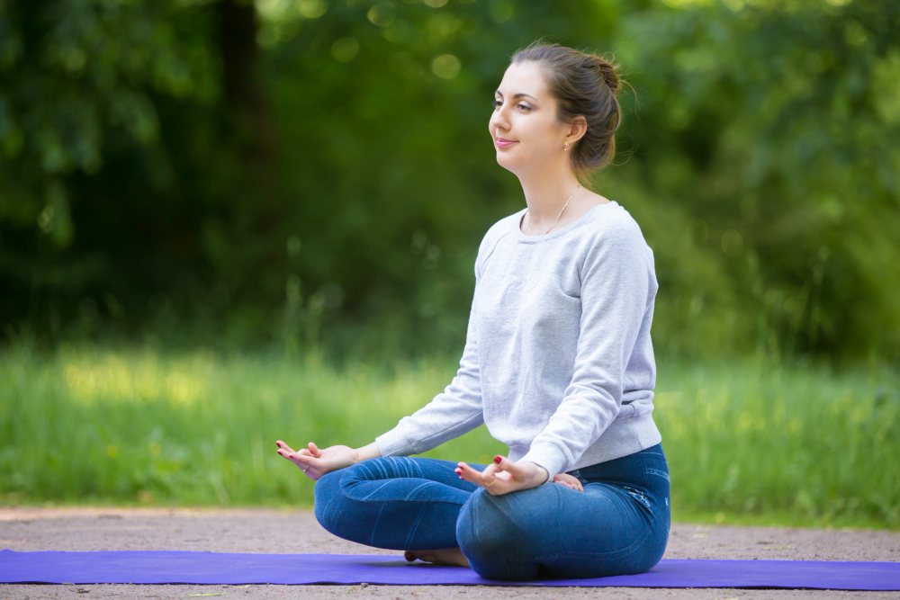 smiling young woman meditating park